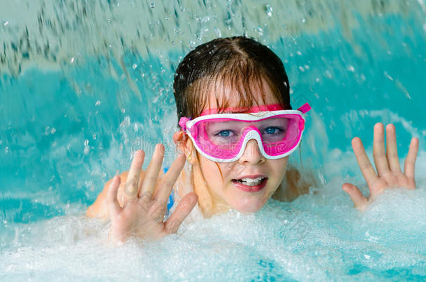 可爱的快乐女孩戴着粉红色的护目镜面具在游泳池里