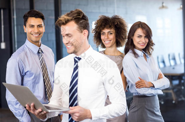 一个商人拿着笔记本电脑站在后面，一个团队站在后面