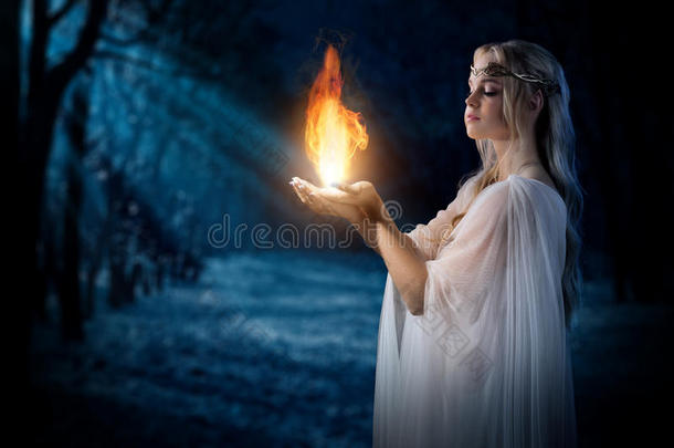 精灵女孩在夜晚的森林里掌着火