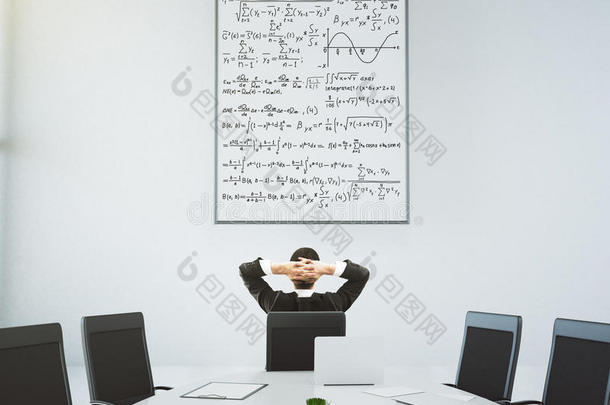 商人在现代会议室看着带<strong>有方</strong>程式的海报，桌子是椭圆形的