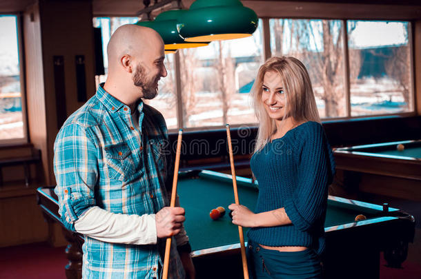 迷人的年轻夫妇互相微笑，打台球