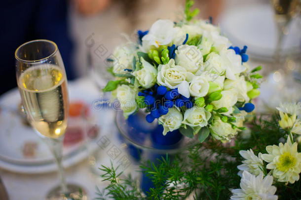 华丽装饰的婚礼桌，花束和一杯香槟在餐厅