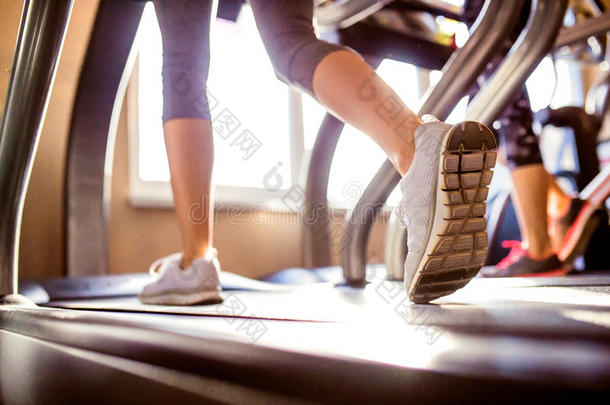 妇女在跑步机健身房跑步的腿的细节