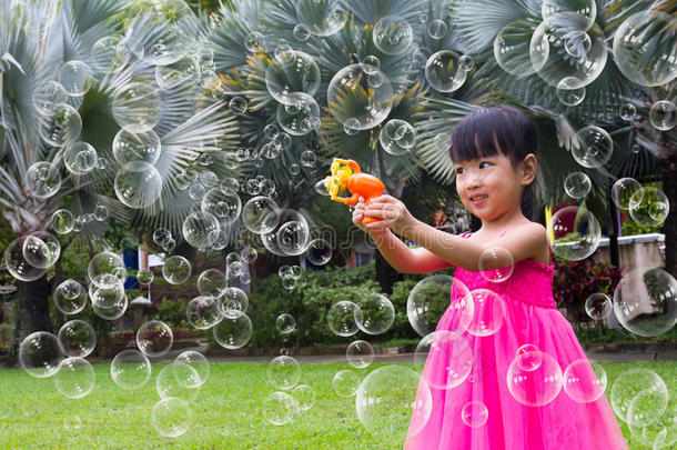 亚洲的中国小女孩从泡泡鼓风机里吹泡泡