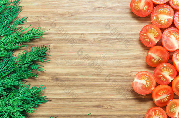 新鲜成熟的红色樱桃西红柿切成两半，新鲜的绿色小条放在木制的<strong>砧板</strong>上。 自然<strong>蔬菜</strong>的概念。 背景