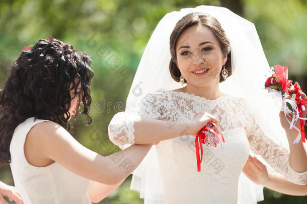优雅华丽的黑发新娘和伴娘手中的红色布托尼埃的自然背景，婚礼日在LVIV
