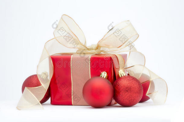 一份红色圣诞礼物，上面有金色的丝带和红色的树装饰