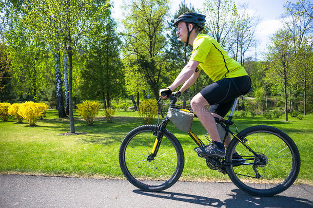 骑自行车的人骑在城市公园的路上。 阳光明媚的夏天炎热的一天
