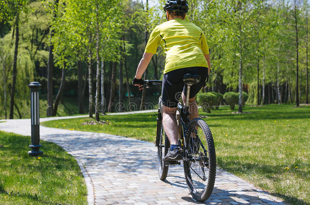 骑自行车的人骑在城市公园的路上。 阳光明媚的夏天炎热的一天