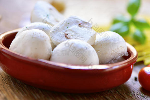 木制桌子上陶器碗里的新鲜蘑菇