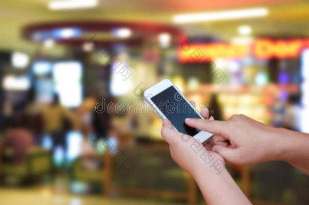 手持和触摸屏智能手机，在抽象模糊的<strong>咖啡店</strong>背景图像上。
