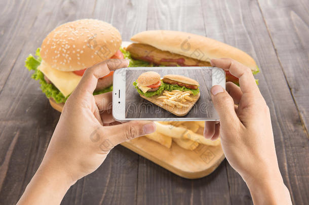 朋友们用智能手机拍热狗和汉堡包的照片