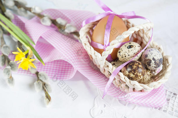 复活节鸡蛋，带丝带在柳条篮子里，旁边是柳树和水仙（黄色水仙）