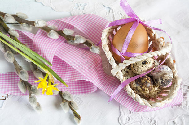 复活节鸡蛋，带丝带在柳条篮子里，旁边是柳树和水仙（黄色水仙）