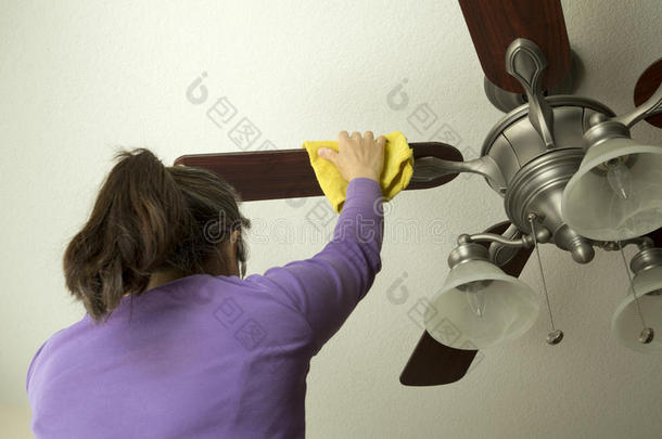 一个女人正在清理吊扇