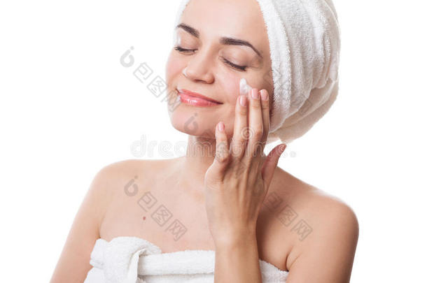 洗澡后，穿着毛巾的女孩在脸上涂上奶油