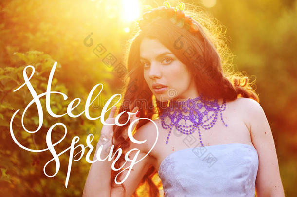美丽快乐的年轻女人在开花的春天花园里享受气味，字母你好冲刺