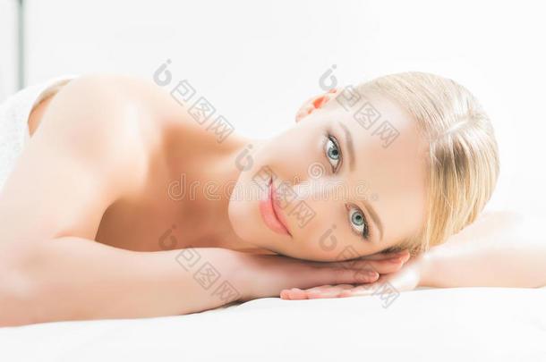 美丽的女人躺在美容院的垫子上