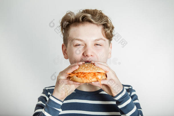 男孩吃汉堡面包，上面有胡萝卜丝