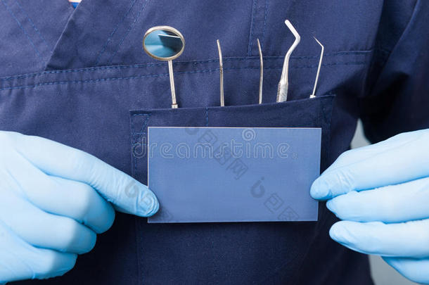 牙科工具和<strong>蓝色</strong>卡片在牙医<strong>手中</strong>的特写