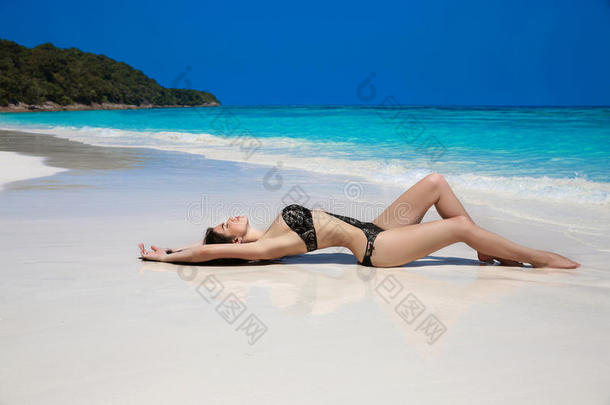 美丽的女人穿着黑色比基尼躺在异国情调的热带