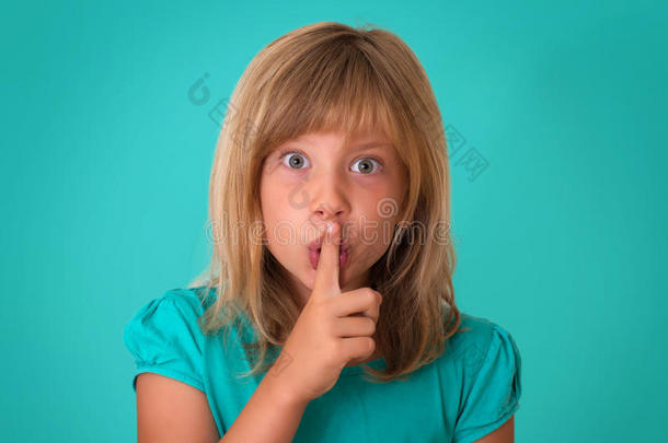 孩子做一个请保持安静的手势朝向相机。 美丽的小女孩把手指贴在嘴唇上，问沉默