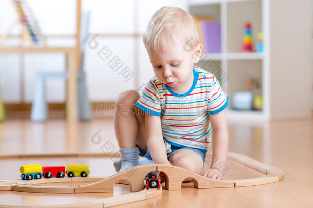 孩子在地板上玩木铁路