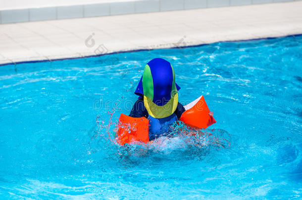 穿着防晒衣的男孩在孩子们的游泳池里玩耍。