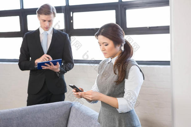 女商人在智能手机上发短信，商人使用数字平板电脑