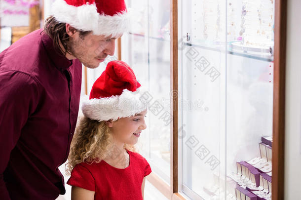 父亲和女儿穿着圣诞服装，看着珠宝展示