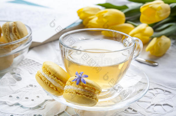 一杯热茶，黄色郁金香，素描本和柠檬马卡龙在一个轻的背景