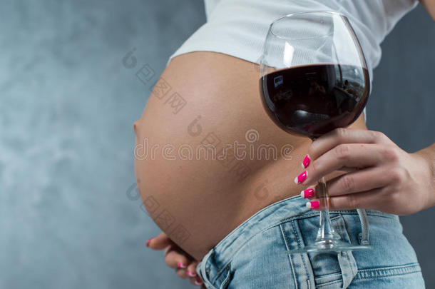一个可爱的怀孕肚子和一杯葡萄酒的特写镜头。