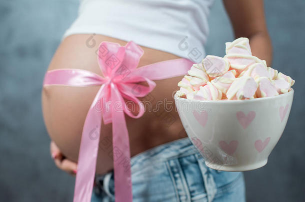 关闭一个可爱的怀孕肚子与粉红色丝带