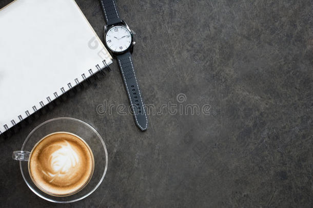 一杯拿铁咖啡，笔记本和黑色背景的手表