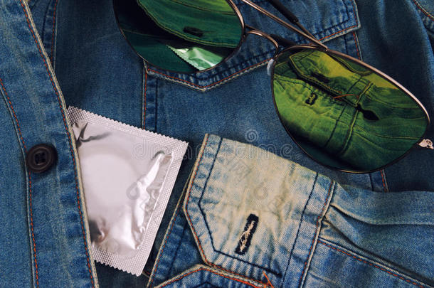 老式蓝色牛仔裤口袋里的避孕套和太阳镜。