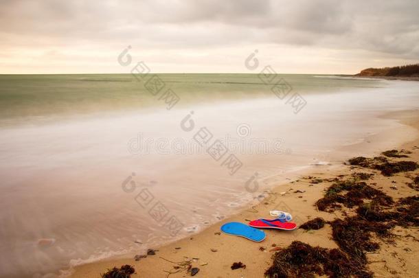 蓝色红色拖鞋和白色<strong>泳镜</strong>，准备在木防波堤的石滩上使用。