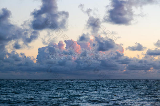 蓬松的乌云漂浮在沙滩岸边汹涌的海水上