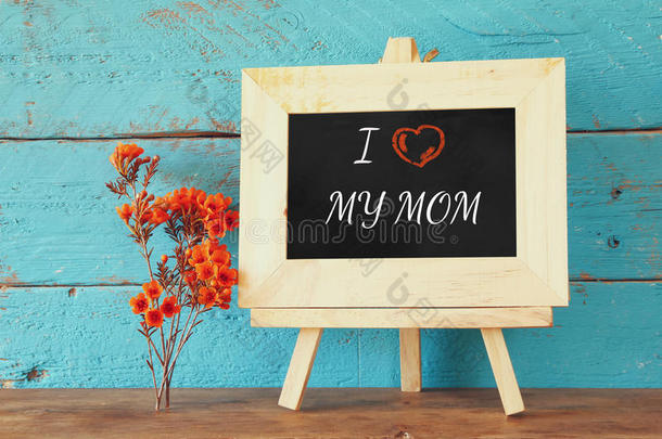 黑板旁边的花有一句话：我爱我妈妈，在木桌上。 快乐母亲节的概念