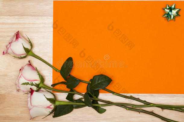 空白橙色页面，白色玫瑰在木制背景上。 复制空间
