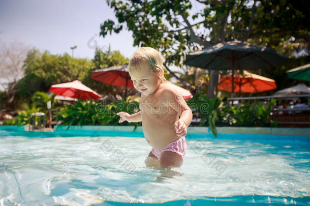 特写小金发女孩微笑着在浅水游泳池里玩耍