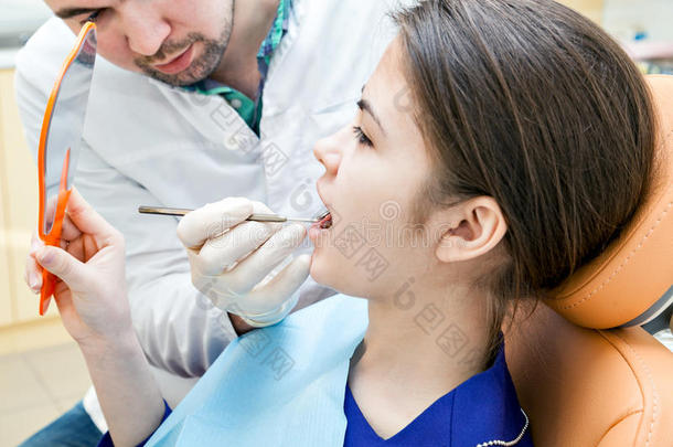 牙科诊所的牙医。 那个在牙医椅子上接待的女孩。
