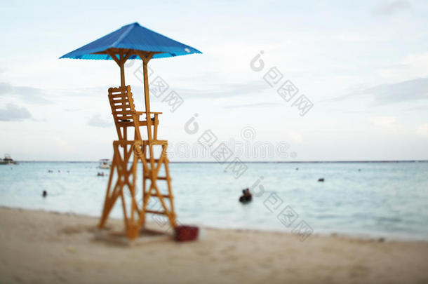 在夏天的日落时，在美丽的海滩上空着一张海湾观察椅。