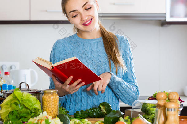 穿套衫的女孩从食谱中学习新的食谱