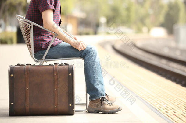 带着复古手提箱在火车站等待的休闲旅行者游客。