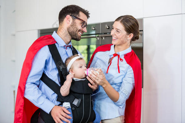 一对穿着超级英雄服装的快乐夫妇给女儿喂牛奶