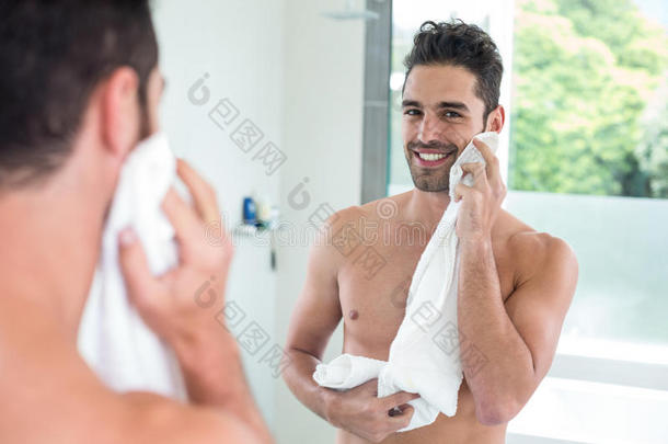英俊的男人一边擦着脸，一边看着镜子