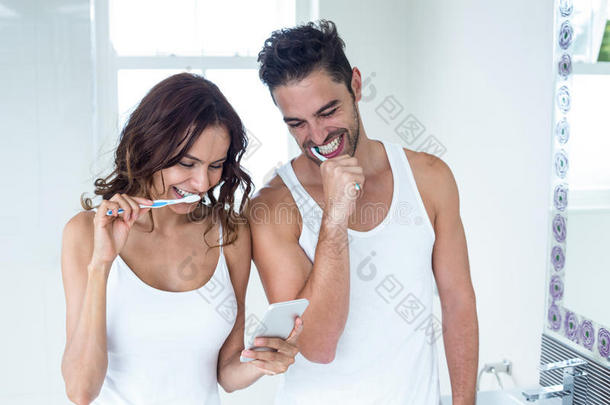 一对夫妇一边刷牙一边看手机