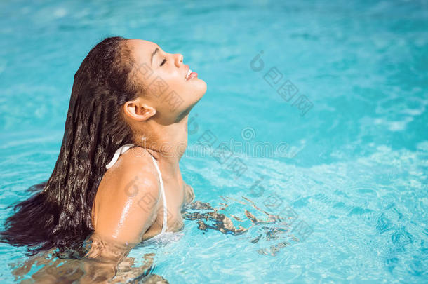 穿着白色比基尼的漂亮女人在游泳池里放松