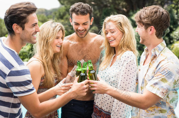 一群朋友在游泳池附近品尝啤酒瓶