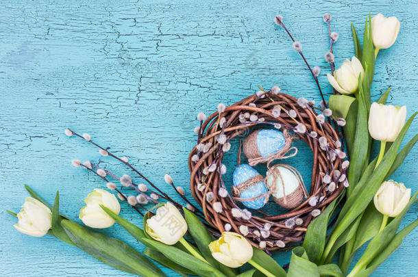 复活节柳树花环，白色郁金香和蓝色复活节彩蛋在蓝色背景